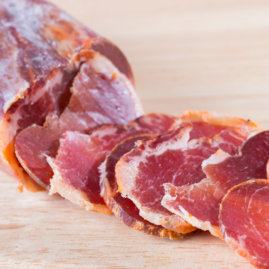 Sliced cured meat on a wooden cutting board