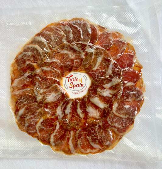 Cured meat product with 'Taste of Spain' label on a white background