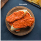 Two slices of bread with Sobrasada iberica fermin on a wooden plate, set against a dark background.