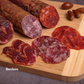 Assorted cured meats on a wooden cutting board with 'ibericos' branding.